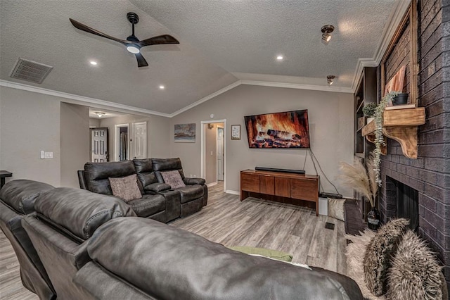 living room with vaulted ceiling, visible vents, wood finished floors, ceiling fan, and a fireplace