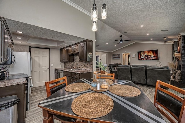 dining area featuring lofted ceiling, a ceiling fan, light wood-style floors, crown molding, and a textured ceiling