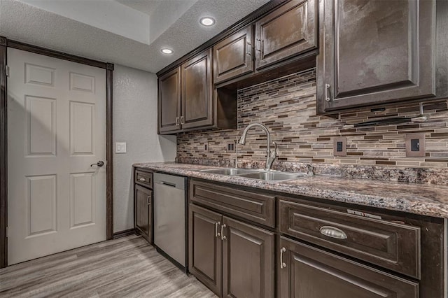 kitchen featuring tasteful backsplash, dishwasher, light wood finished floors, and a sink