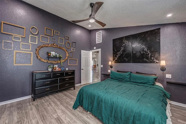 bedroom featuring baseboards, a textured wall, a textured ceiling, and visible vents