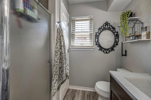 bathroom featuring wood finished floors, a textured wall, toilet, vanity, and baseboards