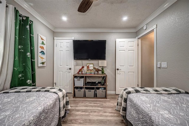 bedroom with a textured wall, ornamental molding, wood finished floors, and a textured ceiling