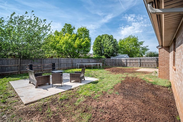view of yard featuring a patio area, a fenced backyard, and a trampoline