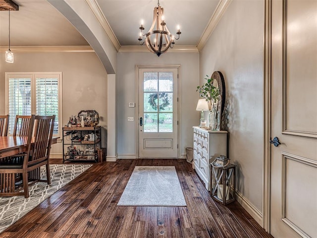 foyer entrance featuring crown molding, an inviting chandelier, arched walkways, dark wood finished floors, and baseboards
