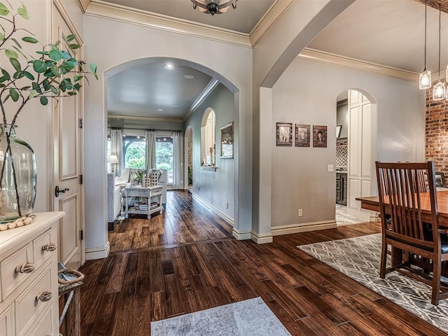 interior space with dark wood-type flooring, arched walkways, baseboards, and crown molding