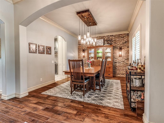 dining area featuring crown molding, arched walkways, and dark wood finished floors