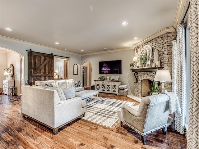 living area featuring crown molding, a barn door, arched walkways, recessed lighting, and wood finished floors