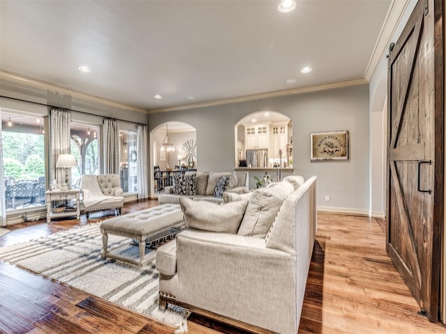 living room featuring arched walkways, recessed lighting, baseboards, light wood-type flooring, and ornamental molding