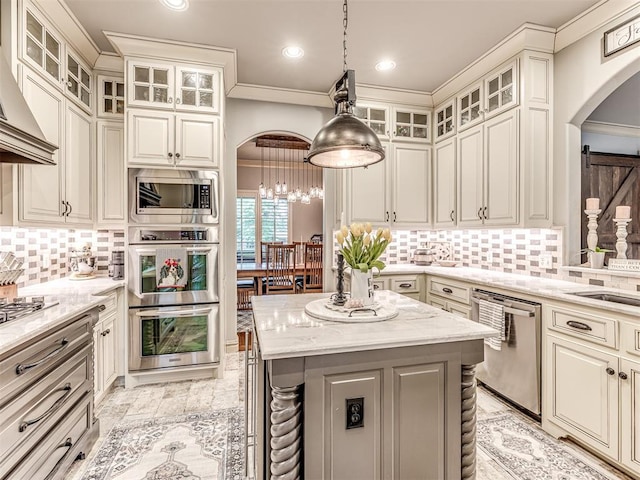 kitchen with appliances with stainless steel finishes, light stone counters, arched walkways, tasteful backsplash, and ornamental molding