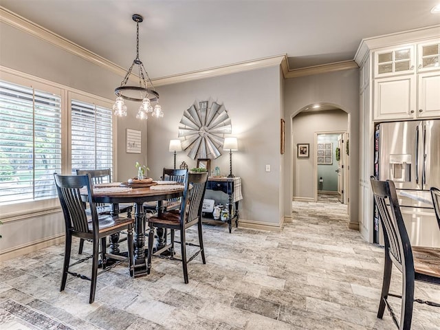 dining area with crown molding, arched walkways, and baseboards