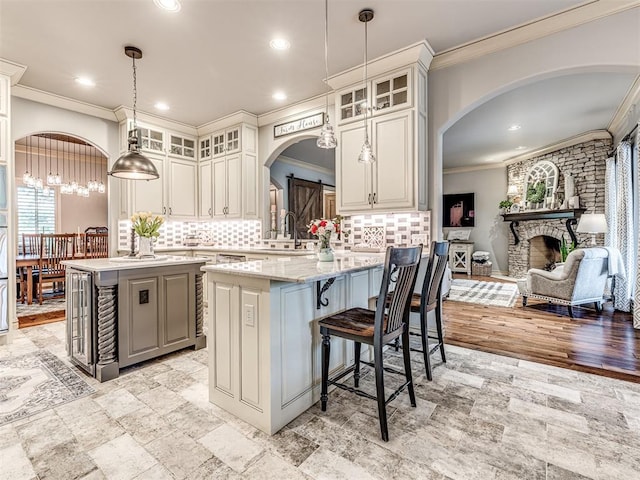 kitchen featuring ornamental molding, a center island, arched walkways, a sink, and backsplash