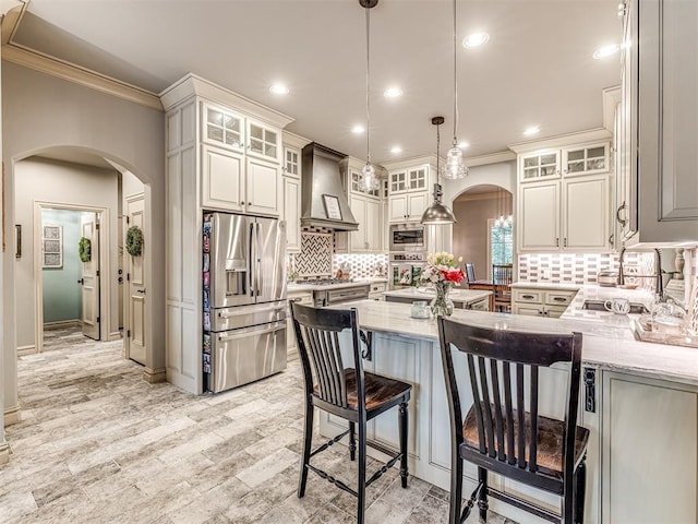 kitchen with crown molding, arched walkways, stainless steel appliances, and wall chimney exhaust hood