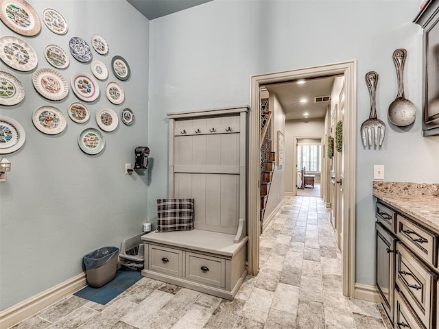 mudroom with baseboards, stone finish floor, and visible vents