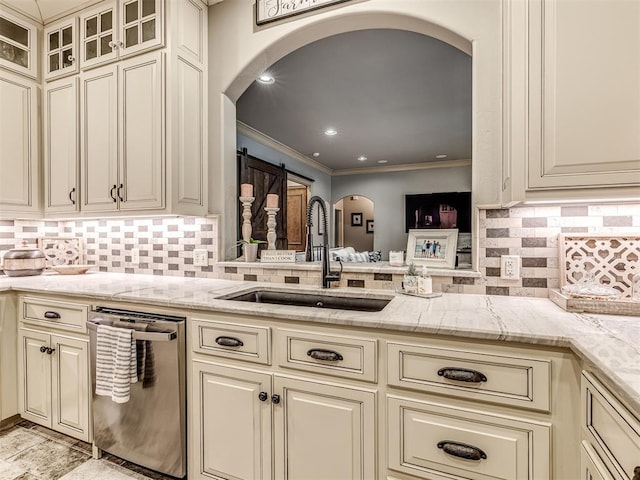 kitchen featuring arched walkways, dishwasher, and cream cabinetry