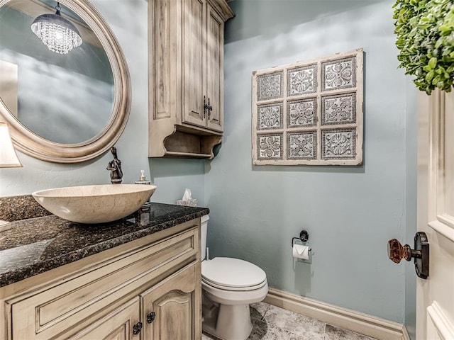 bathroom with toilet, baseboards, a chandelier, and vanity