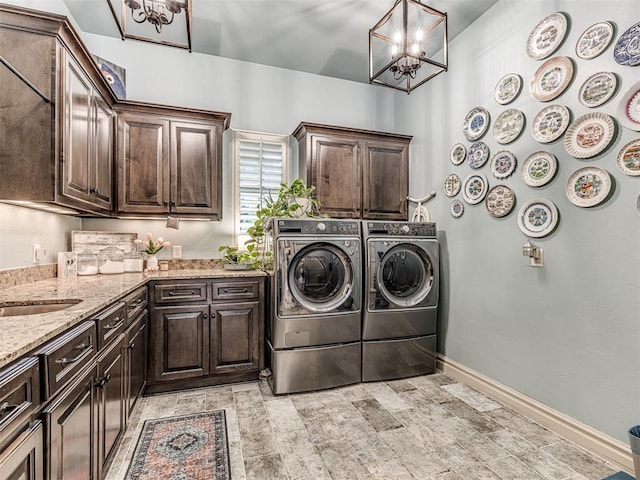 clothes washing area featuring baseboards, cabinet space, independent washer and dryer, and a chandelier