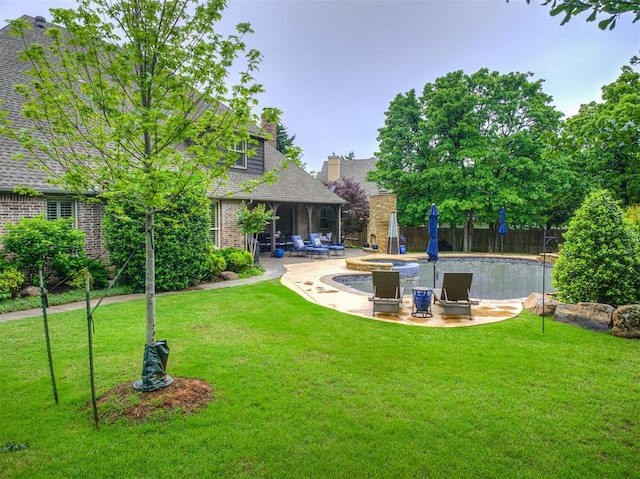 view of yard featuring a patio area, fence, and a pool with connected hot tub