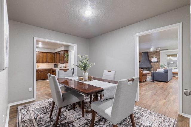 1312 N Nail Pkwy, Moore, OK 73160 - dining room featuring light wood-style floors, a textured ceiling, ceiling fan, and baseboards