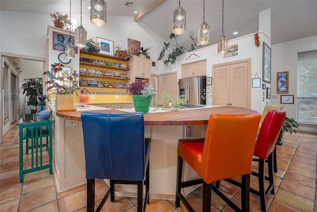 kitchen with stainless steel refrigerator with ice dispenser, hanging light fixtures, beamed ceiling, wood counters, and a breakfast bar