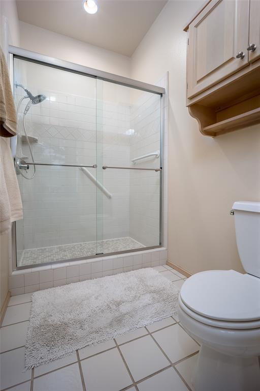 full bathroom featuring toilet, tile patterned floors, recessed lighting, and a shower stall