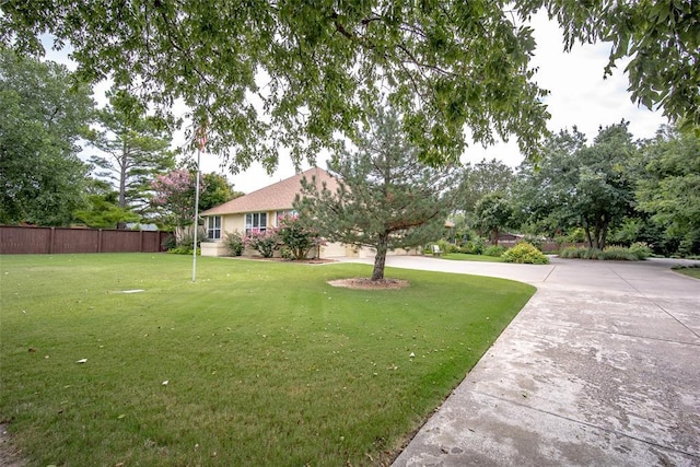 view of yard featuring a garage, fence, and driveway
