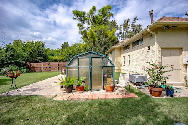 rear view of house featuring a patio area, an exterior structure, an outdoor structure, a fenced backyard, and a yard