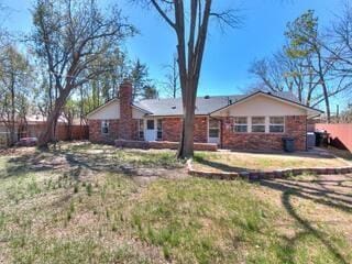 rear view of property with fence, a yard, and a chimney