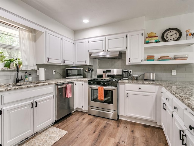 kitchen with backsplash, appliances with stainless steel finishes, a sink, white cabinets, and under cabinet range hood