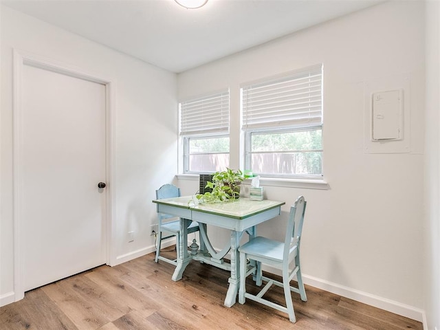 dining space with light wood-style floors, baseboards, and electric panel