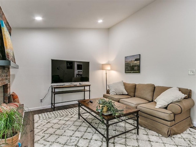 living room featuring baseboards, a fireplace, recessed lighting, and wood finished floors