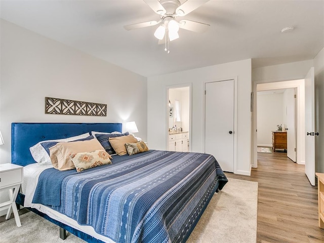 bedroom with connected bathroom, ceiling fan, baseboards, and light wood-style flooring