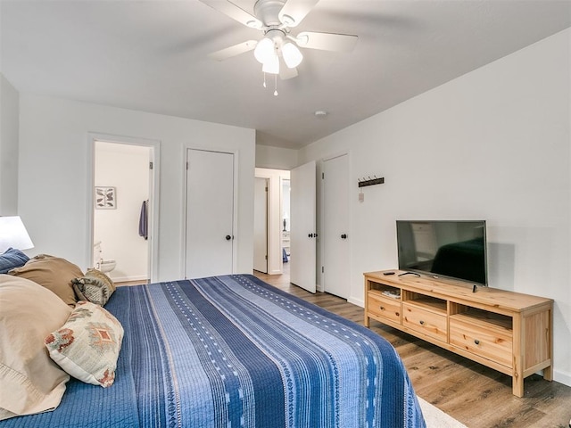 bedroom with baseboards, ensuite bathroom, wood finished floors, and ceiling fan