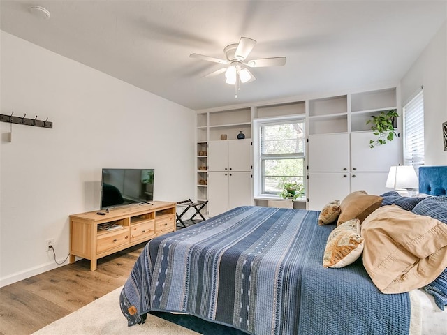 bedroom featuring baseboards, a ceiling fan, wood finished floors, and multiple windows