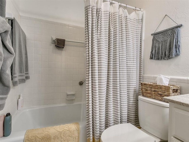 full bath with vanity, toilet, tile walls, and shower / tub combo