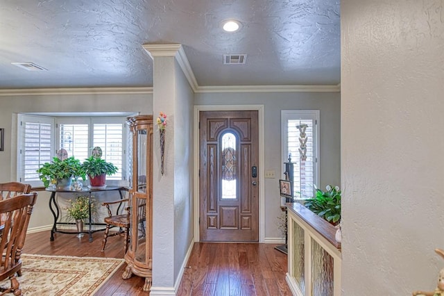 entrance foyer featuring baseboards, a textured wall, hardwood / wood-style floors, and visible vents