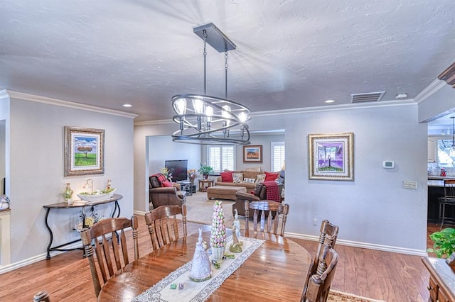 dining space featuring a notable chandelier, plenty of natural light, wood finished floors, and visible vents