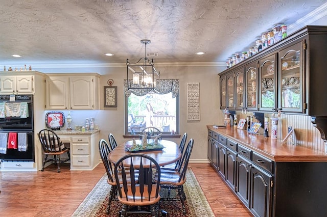 dining area with crown molding, light wood-style floors, a chandelier, baseboards, and visible vents
