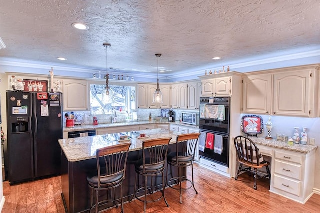 kitchen with a sink, a textured ceiling, a center island, light wood-type flooring, and black appliances