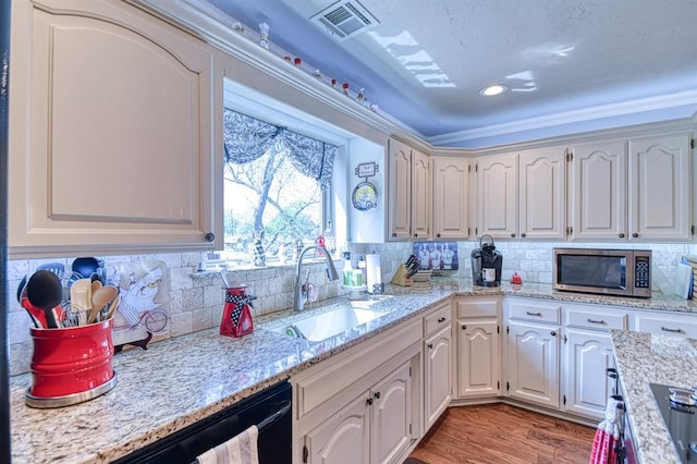 kitchen with visible vents, a sink, stainless steel microwave, and backsplash