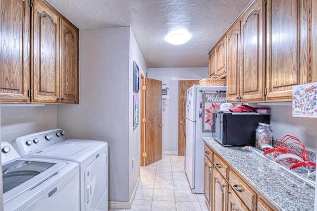 laundry room featuring light tile patterned floors, a textured ceiling, cabinet space, and washer and dryer