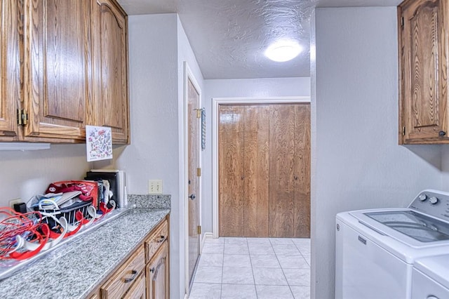 laundry room with cabinet space, independent washer and dryer, a textured ceiling, and light tile patterned flooring