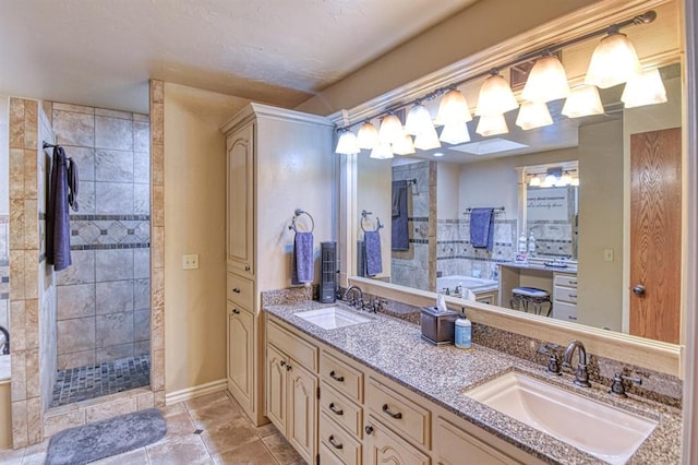 bathroom featuring double vanity, tile patterned floors, a tile shower, and a sink