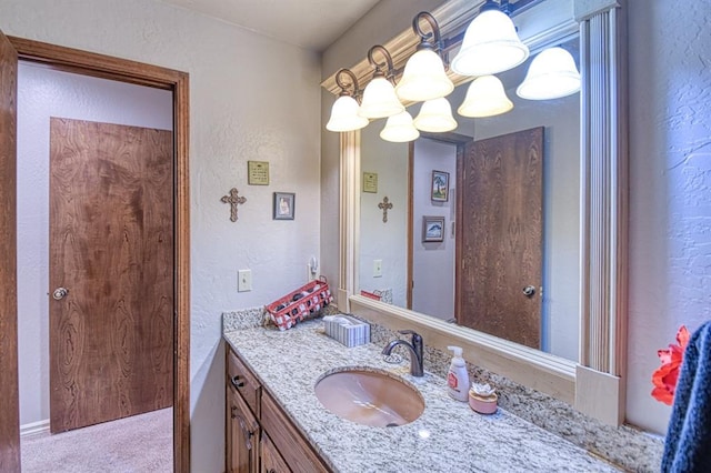 bathroom with a textured wall, a notable chandelier, and vanity