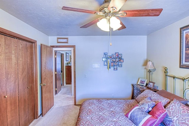 bedroom featuring a closet, a textured ceiling, ceiling fan, and light carpet