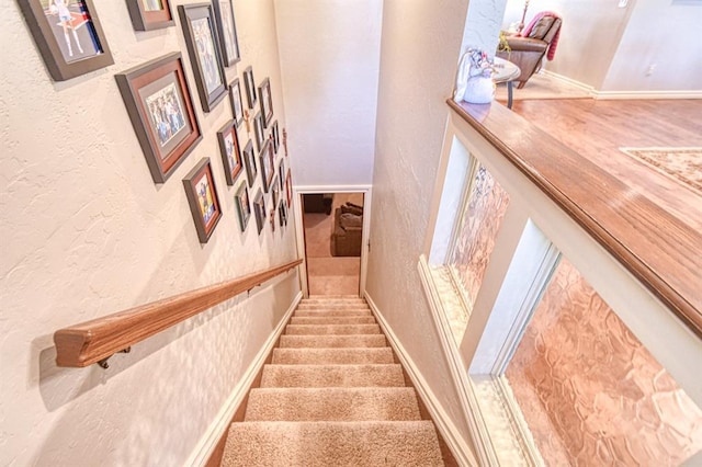 stairway with baseboards and a textured wall