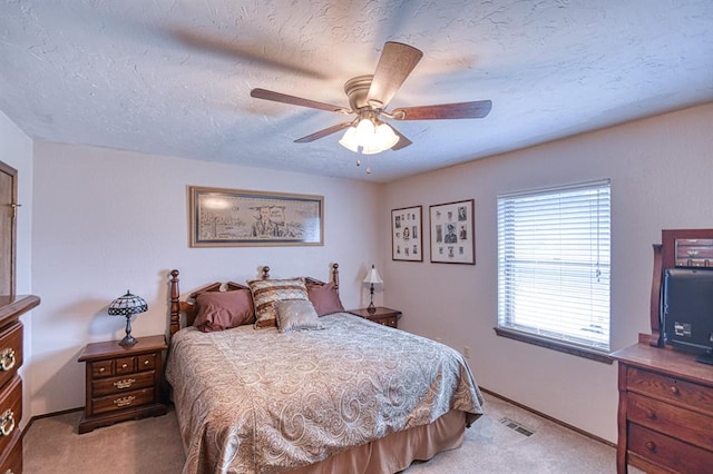 bedroom featuring baseboards, visible vents, a textured ceiling, and light colored carpet