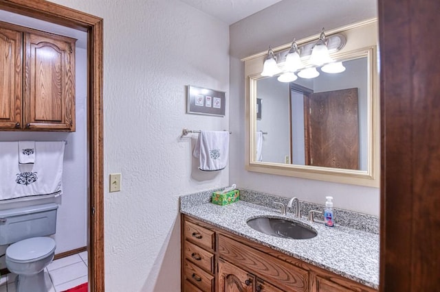 bathroom featuring tile patterned flooring, a textured wall, toilet, and vanity