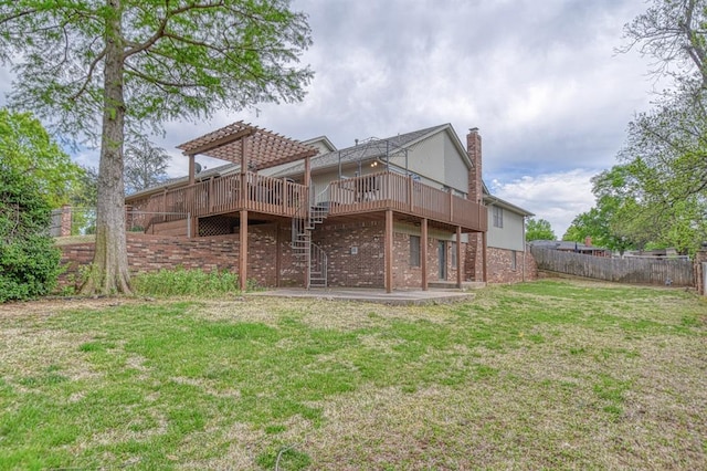 rear view of house featuring fence, stairs, brick siding, a deck, and a lawn
