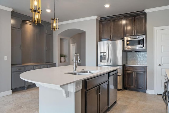 kitchen featuring arched walkways, a sink, backsplash, appliances with stainless steel finishes, and ornamental molding