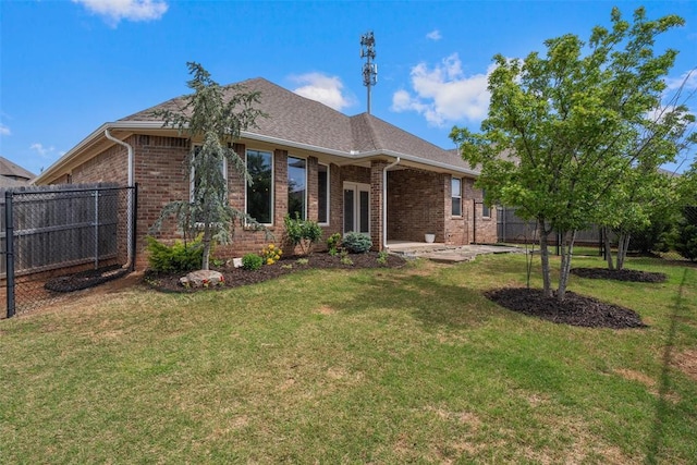 back of house featuring a lawn, brick siding, and fence